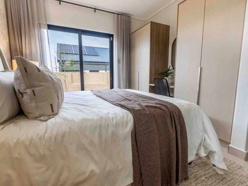 A well-appointed bedroom featuring modern built-in cupboards and a sliding glass door that provides access to the exterior.