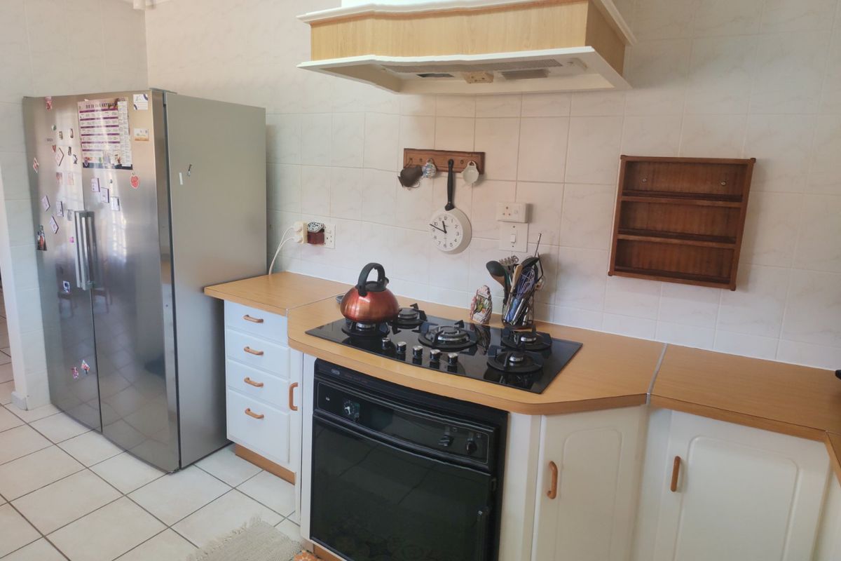 A functional kitchen featuring a built-in oven, gas hob, extractor fan, laminate countertops, and tiled splashback with neutral cabinetry.