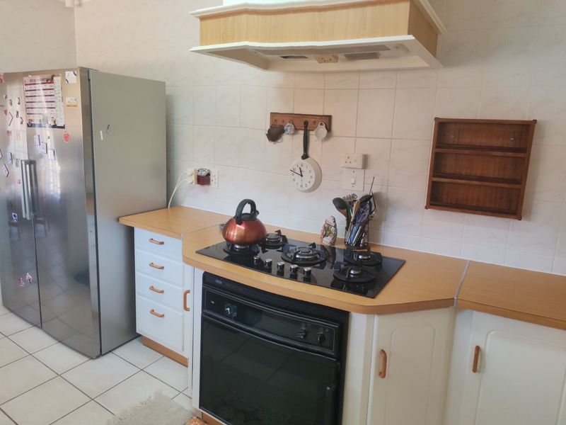 A functional kitchen featuring a built-in oven, gas hob, extractor fan, laminate countertops, and tiled splashback with neutral cabinetry.