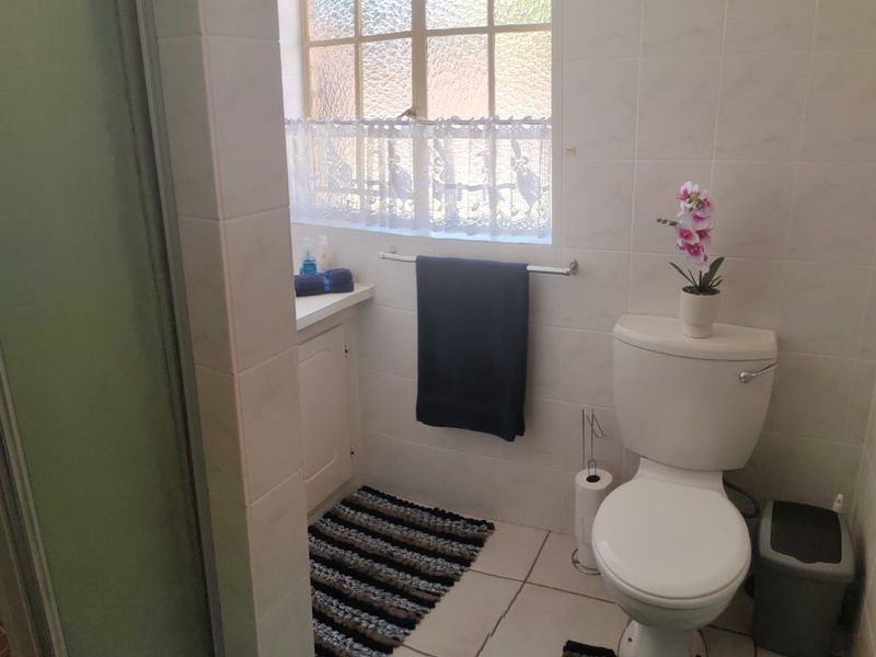 A functional bathroom featuring a shower enclosure, toilet, and vanity cabinet with tiled finishes throughout.
