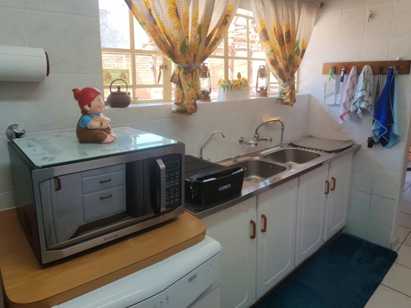 A functional kitchen area featuring a double stainless steel sink, tiled splashbacks, and built-in cabinetry with ample counter space.