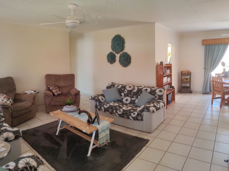 Spacious open-plan living and dining area featuring neutral tiled flooring, ceiling fans, and a functional layout suitable for family living.