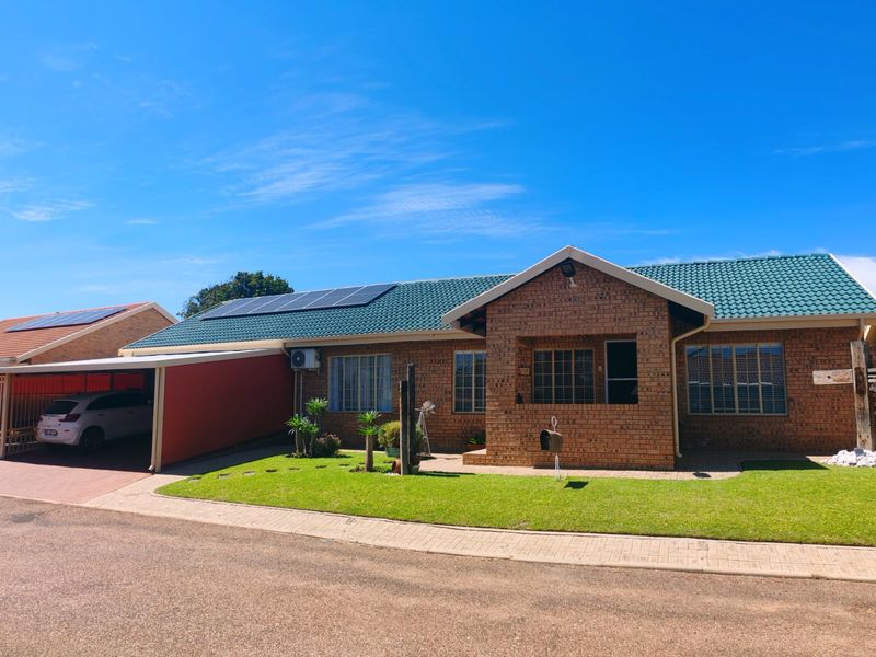 A well-maintained face brick house featuring a tiled roof, solar panels, a paved driveway, and an attached carport.