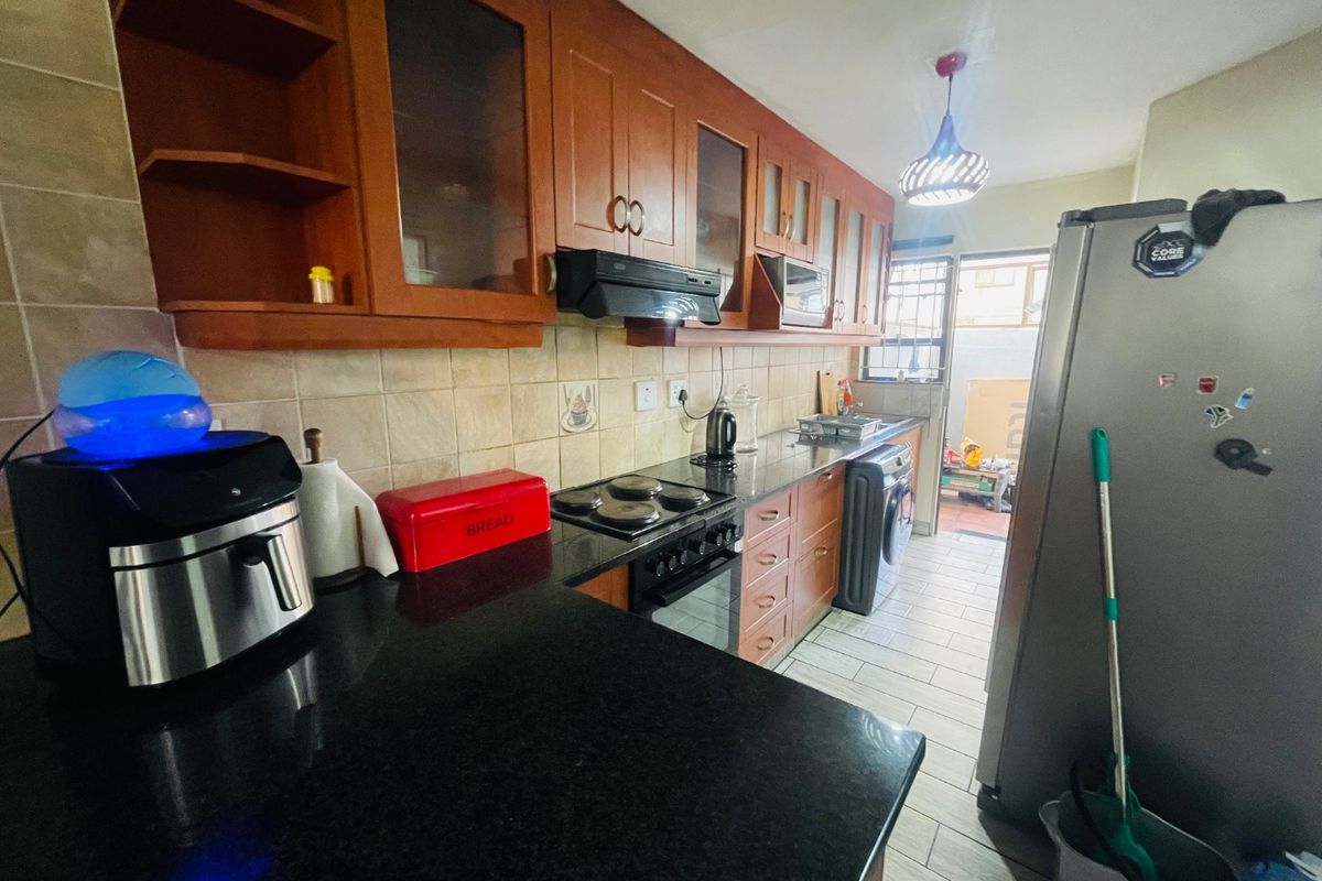 A functional kitchen featuring wooden cabinetry, granite countertops, and a tiled backsplash, with direct access to an outdoor area.