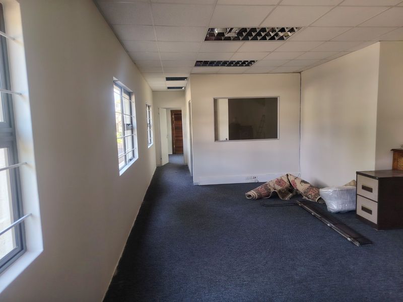 A vacant commercial office space featuring a suspended ceiling, recessed lighting, carpeted flooring, and an internal window partition, suitable for various business configurations.