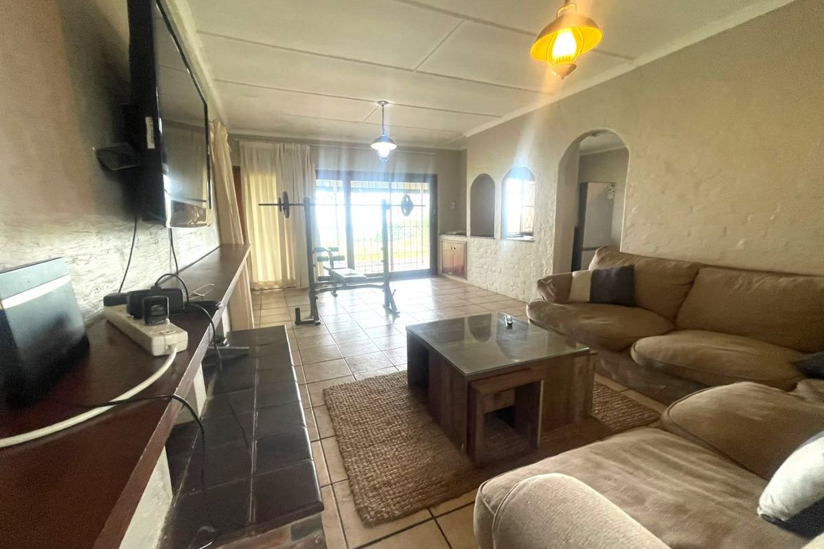 Spacious living room featuring tiled flooring, a built-in fireplace, and arched architectural details, with direct access to the outdoor area through sliding glass doors.