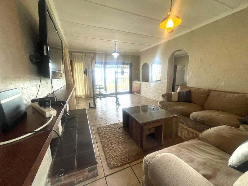 Spacious living room featuring tiled flooring, a built-in fireplace, and arched architectural details, with direct access to the outdoor area through sliding glass doors.