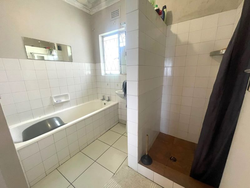 A functional bathroom featuring a separate bathtub and tiled shower enclosure, requiring cosmetic updates to modernize the finishes and address ceiling wear.