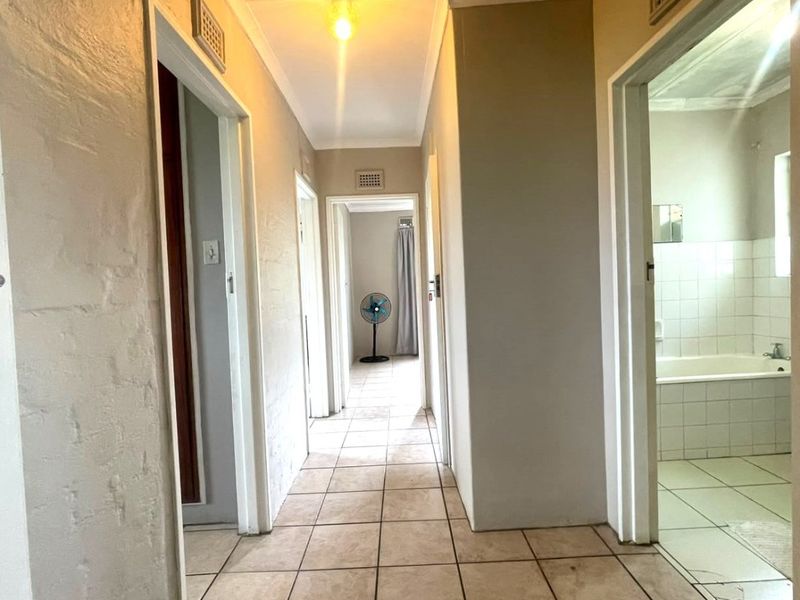 A functional hallway featuring tiled flooring and access to multiple rooms, including a bathroom with a built-in bathtub.