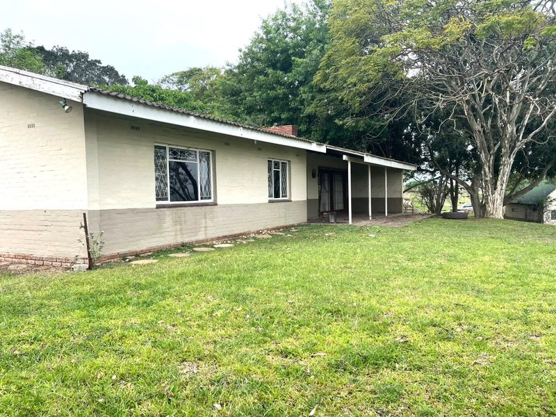Rear view of the property featuring a covered patio area, brick exterior walls, and a spacious garden setting.