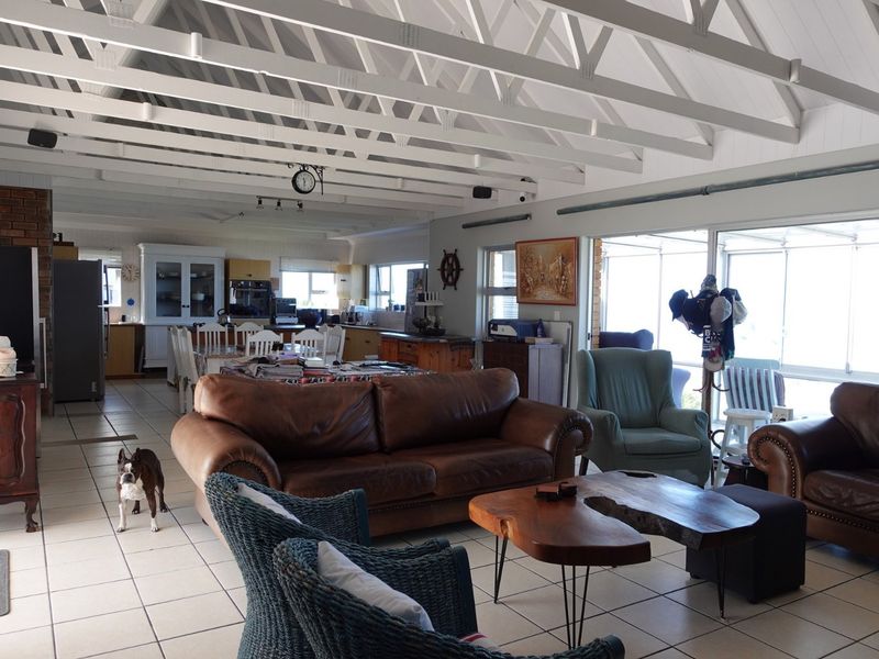 Spacious open-plan living and dining area featuring vaulted ceilings with exposed beams, tiled flooring, and large sliding doors providing ample natural light.