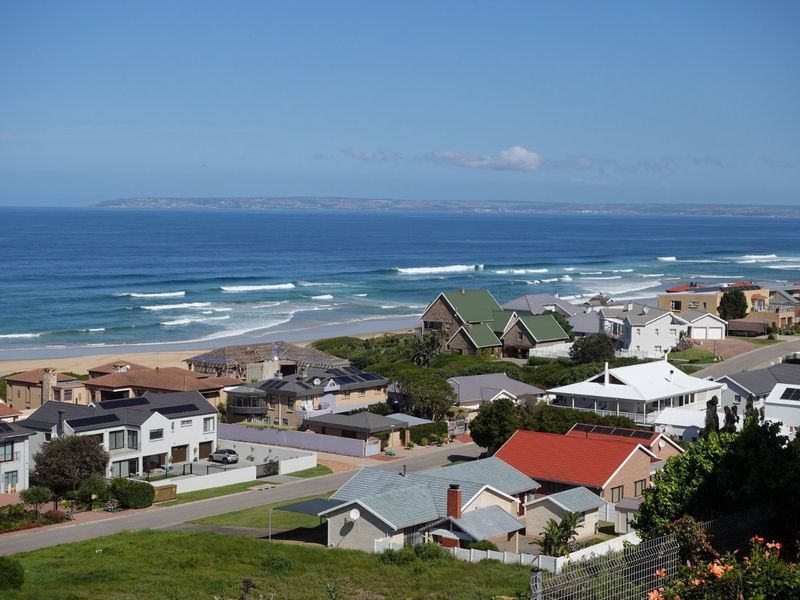 A scenic elevated view overlooking a coastal residential neighborhood with direct access to the beach and ocean.