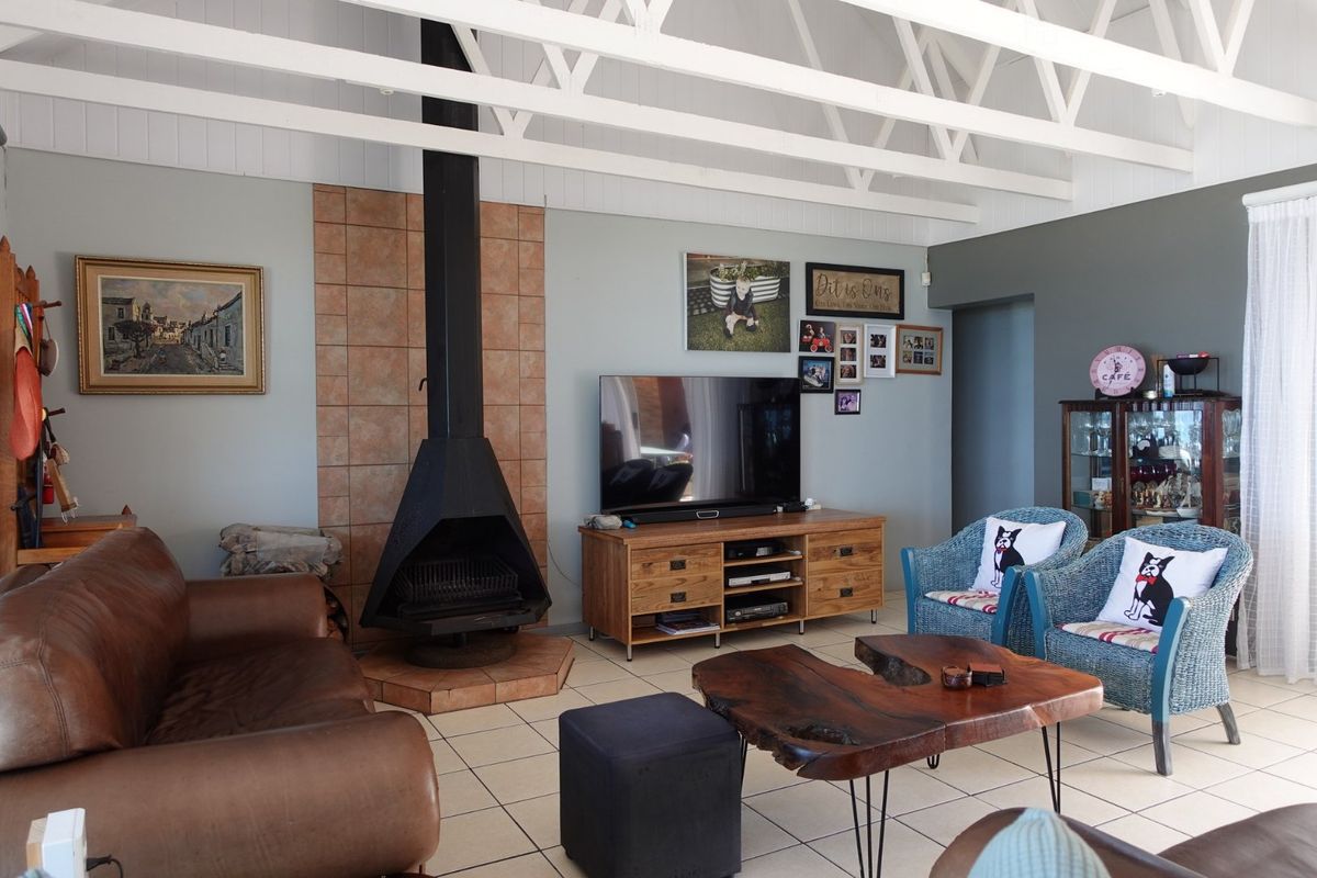 Spacious living room featuring a prominent freestanding fireplace with tiled hearth, exposed white roof trusses, and neutral tiled flooring.