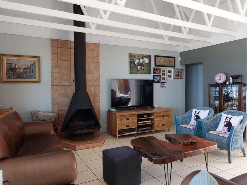 Spacious living room featuring a prominent freestanding fireplace with tiled hearth, exposed white roof trusses, and neutral tiled flooring.