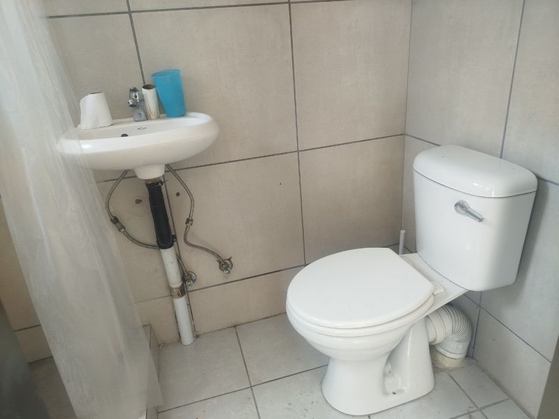 A compact bathroom featuring a wall-mounted basin and a standard toilet with tiled finishes throughout.