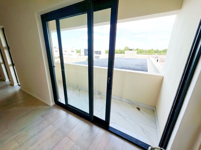 A modern balcony featuring tiled flooring and a sliding glass door, offering an open outdoor space accessible from the interior.