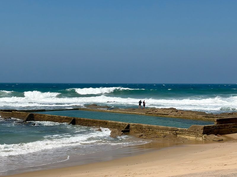 A scenic view of a coastal tidal pool set against the backdrop of the ocean and breaking waves.