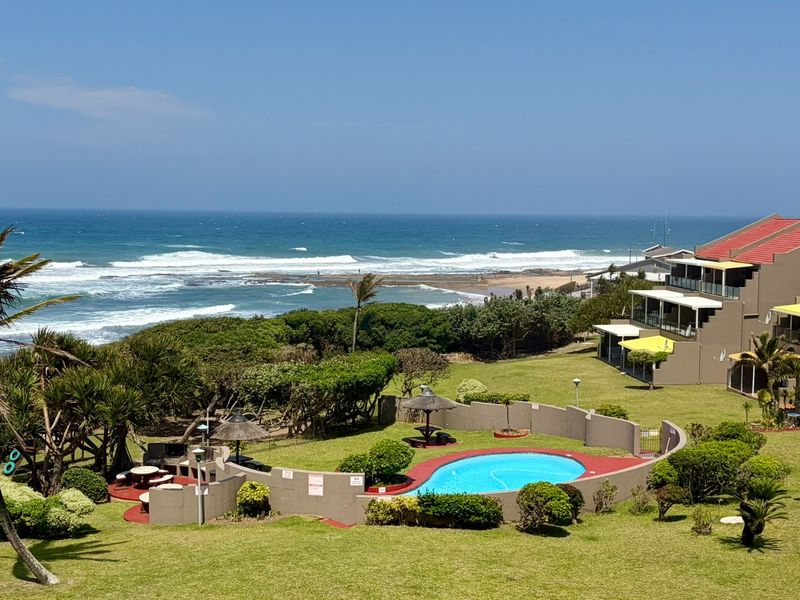 A well-maintained communal pool area set within landscaped grounds, featuring ocean views and direct access to the coastal environment.