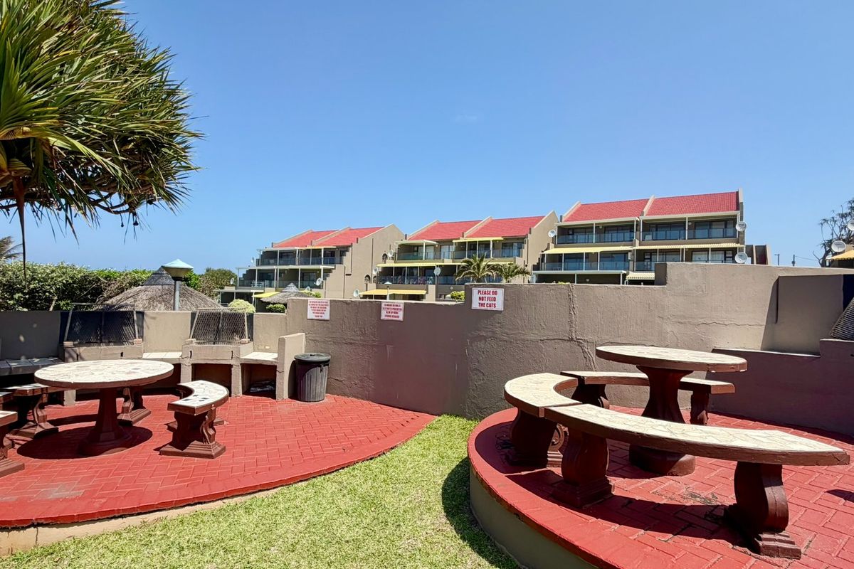 Communal outdoor entertainment area featuring built-in braai facilities, paved seating areas, and landscaped garden space within the apartment complex.
