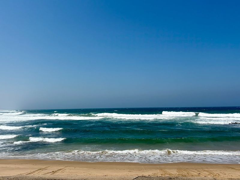 A scenic view of the ocean and sandy beach, showcasing the natural coastal landscape.
