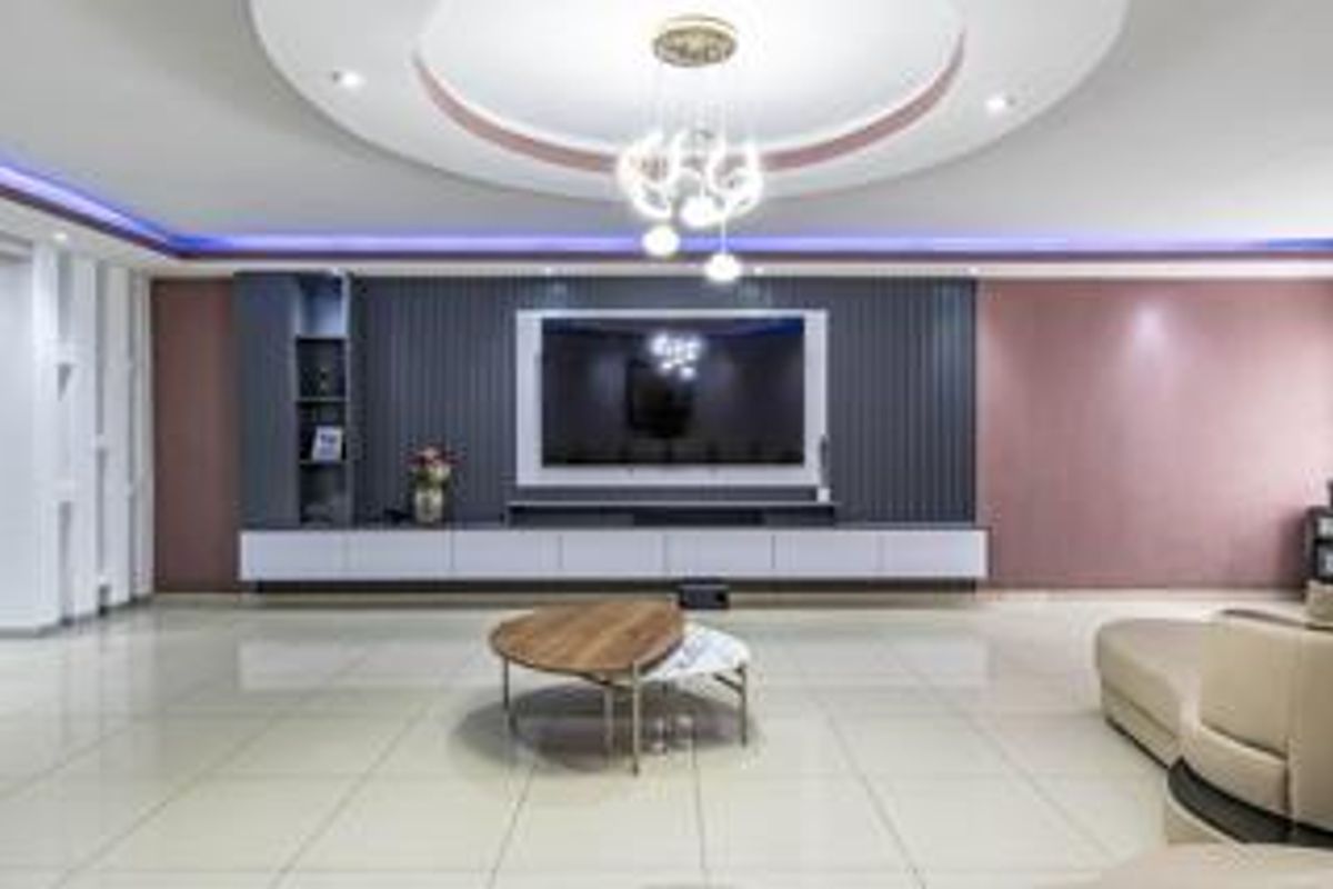 Modern living room featuring a custom built-in media wall, recessed ceiling with ambient LED lighting, and polished tiled flooring.