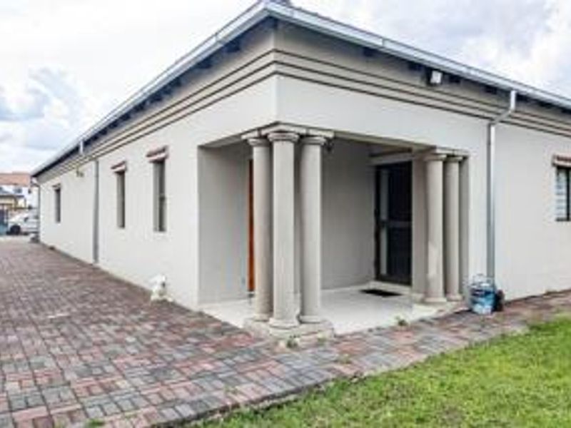 Front elevation of a single-story house featuring a covered entrance with decorative columns and paved driveway access.
