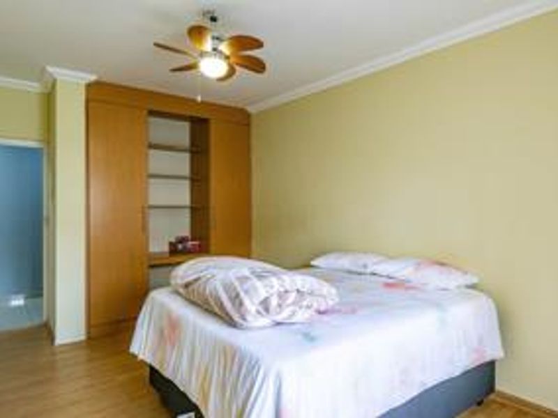 A bedroom featuring laminate flooring, a ceiling fan, and a built-in wooden wardrobe with integrated shelving.