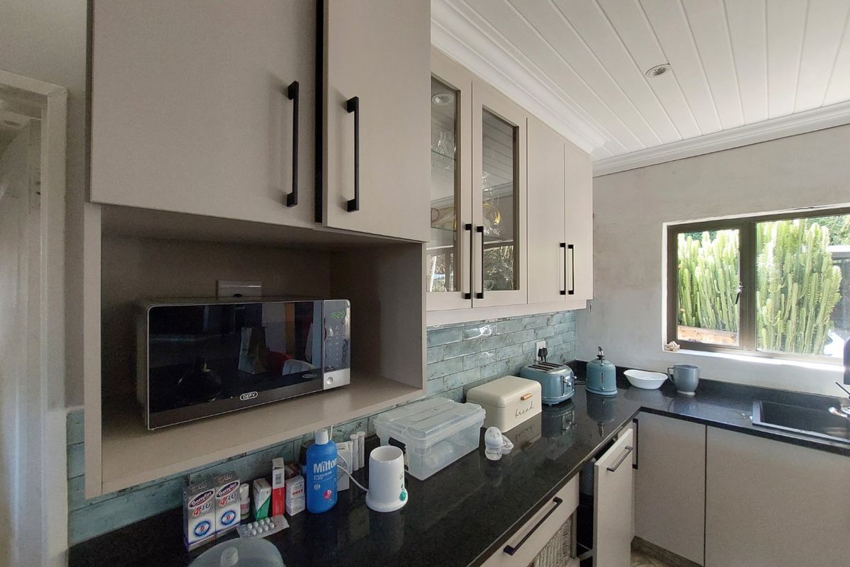 A well-maintained kitchen featuring modern neutral cabinetry, dark granite countertops, a stylish subway tile backsplash, and a built-in microwave.