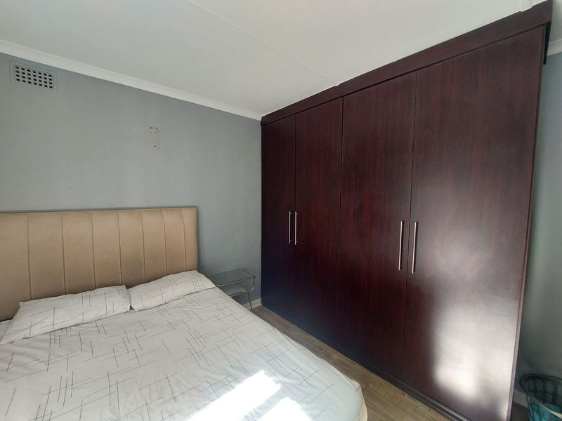A bedroom featuring dark wood built-in cupboards and neutral wall finishes.