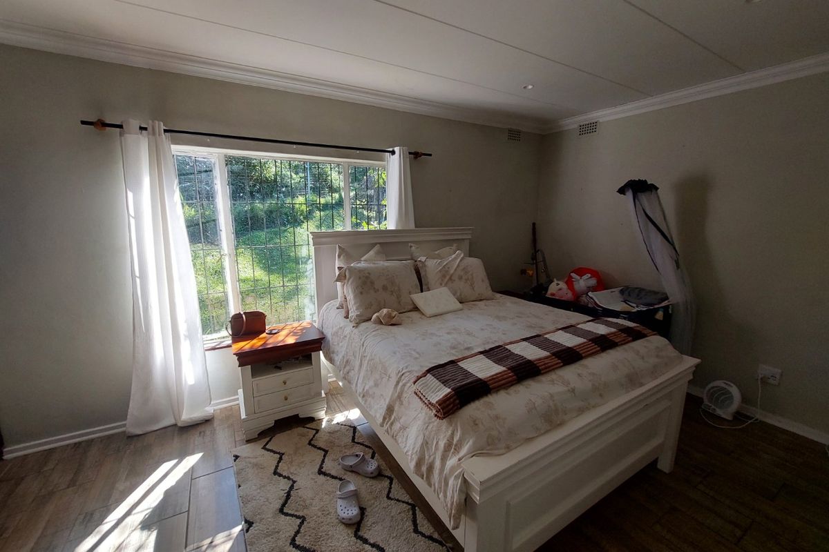 A bedroom featuring tiled flooring, recessed ceiling lighting, and a window fitted with security bars, offering natural light and a view of the garden.