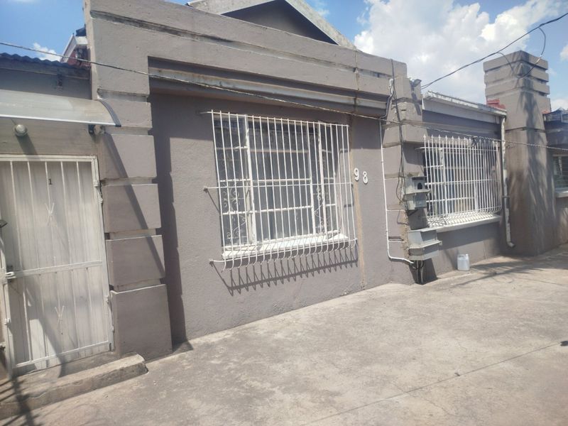 Front facade of a residential property featuring security bars on windows, a concrete driveway, and a secure entrance gate.