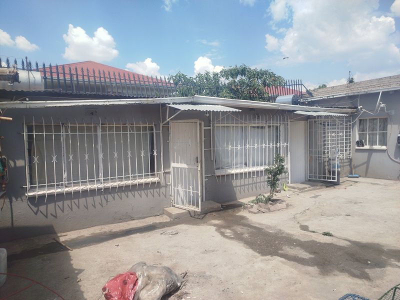 Rear exterior view of the property featuring concrete paving, security bars on windows, and a solar geyser installation on the roof.