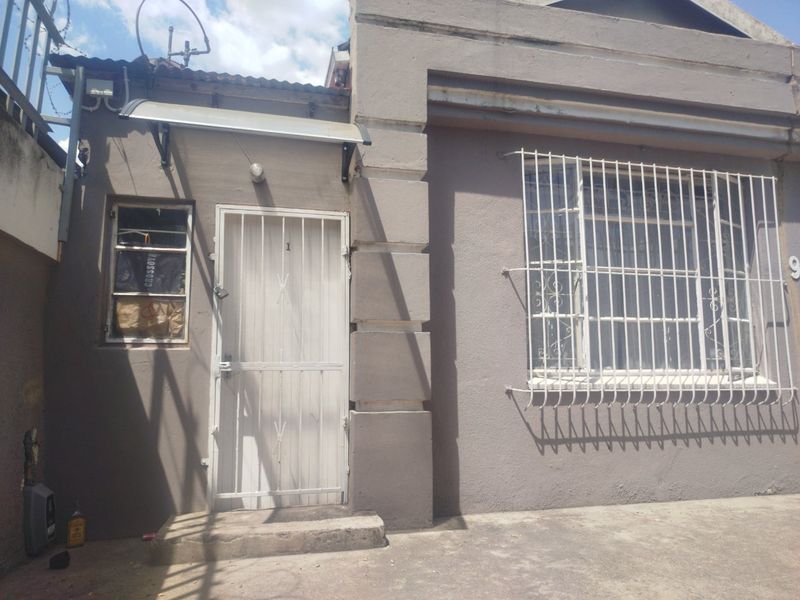 Front exterior view of the property featuring a security gate, protective window bars, and a concrete entrance area.