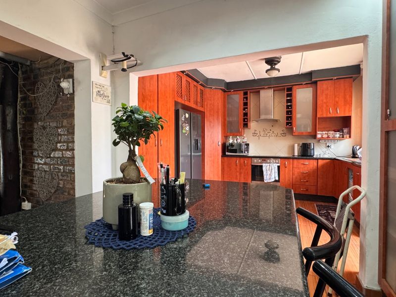 A functional kitchen featuring wooden cabinetry, a granite-topped island, and an exposed brick feature wall, offering a warm and practical cooking space.