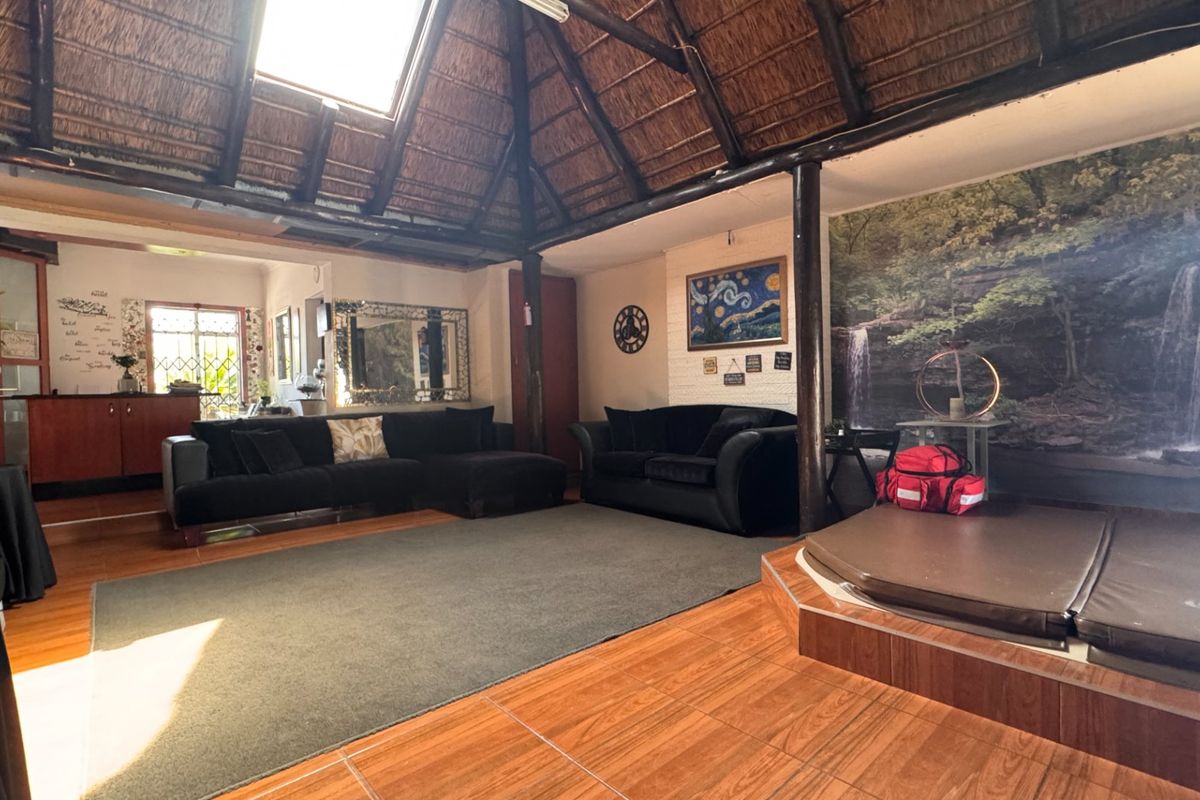 Spacious living area featuring a unique thatched roof with a skylight, exposed timber support poles, and a built-in raised platform area.