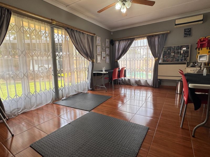 A spacious living area featuring tiled flooring, a ceiling fan, split-system air conditioning, and large sliding glass doors with security gates leading outdoors.