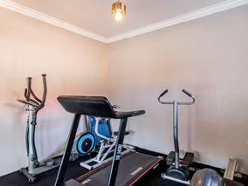 A dedicated home gym space featuring neutral wall finishes and decorative ceiling coving.