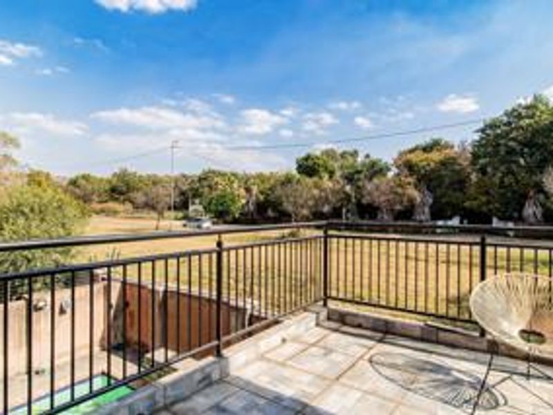 An elevated balcony featuring a metal balustrade and tiled flooring, offering an open view of the surrounding landscape.