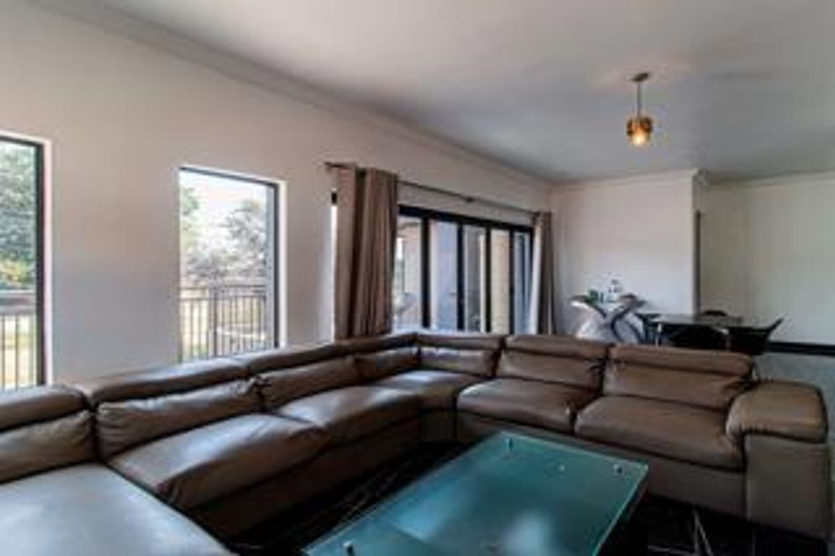 Spacious living room featuring large windows, sliding glass doors leading to an outdoor area, and modern recessed and pendant lighting.