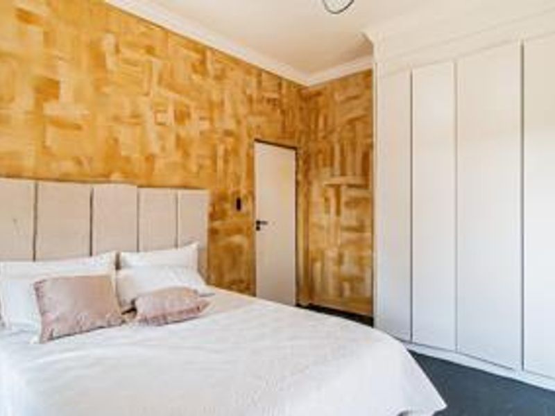 Bedroom featuring built-in cupboards and textured feature walls, providing ample storage space and a distinct aesthetic.
