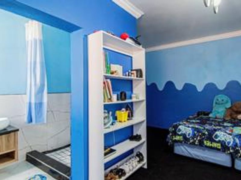 Bedroom featuring an open-plan en-suite bathroom with a vanity basin and shower, finished with bold blue wall paint.