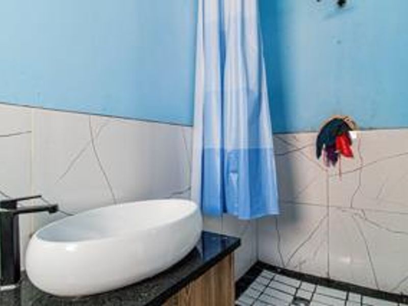 A bathroom featuring a modern vessel sink with a black faucet, vanity cabinet, and marble-effect wall tiles, requiring minor cosmetic repairs to the wall finish.
