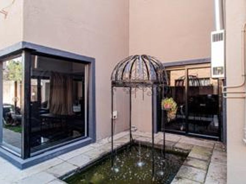 Rear courtyard area featuring a decorative metal water fountain, paved flooring, and large sliding glass doors providing access to the interior living space.