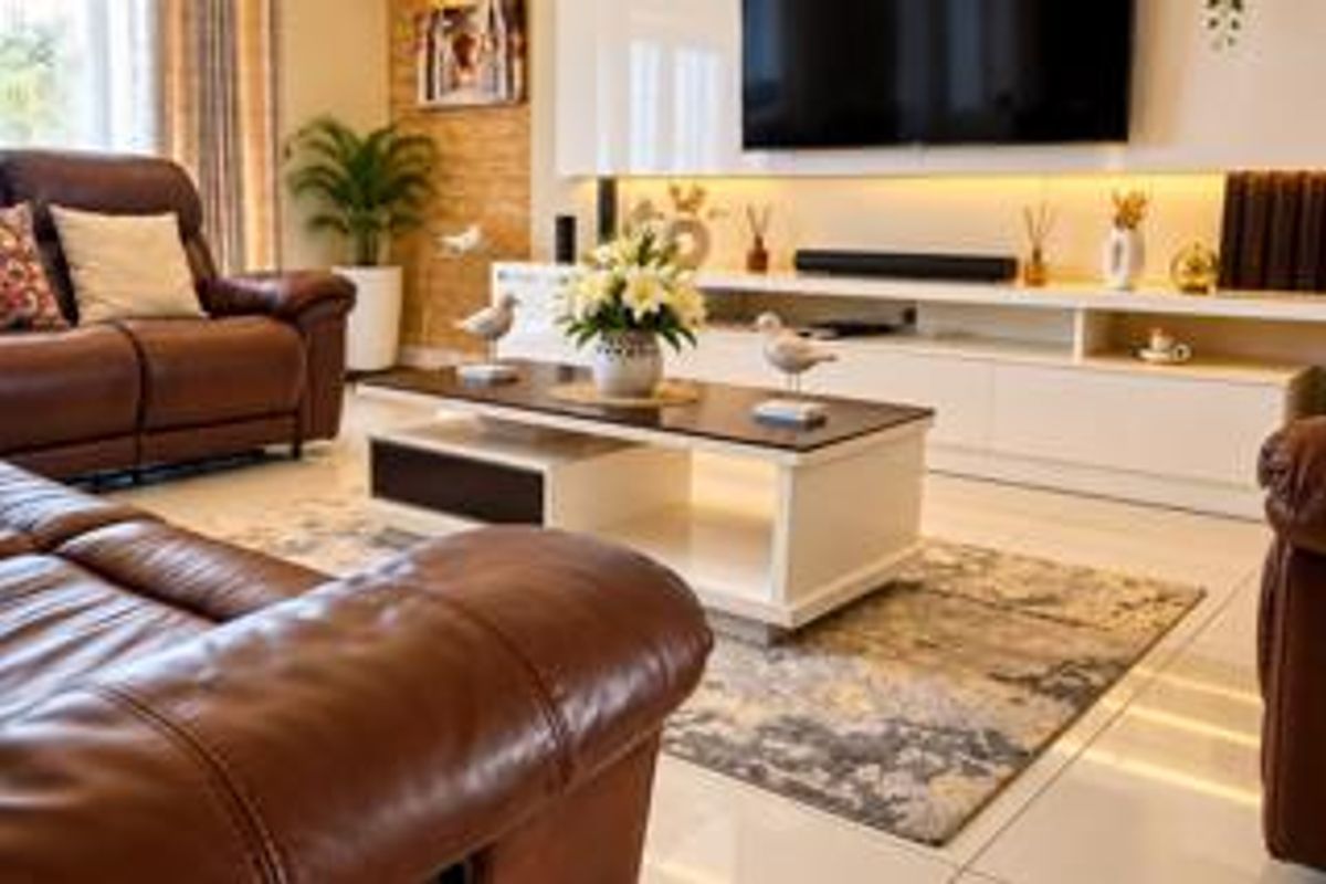 A modern living room featuring a sleek built-in media console, recessed lighting, and a textured stone feature wall with polished tiled flooring.