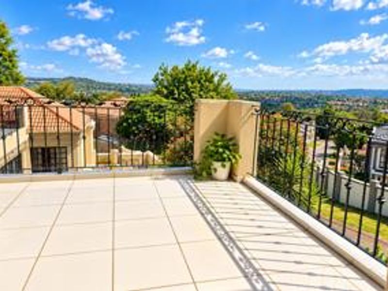 A spacious balcony featuring tiled flooring and a wrought iron balustrade, offering expansive elevated views of the surrounding neighbourhood.