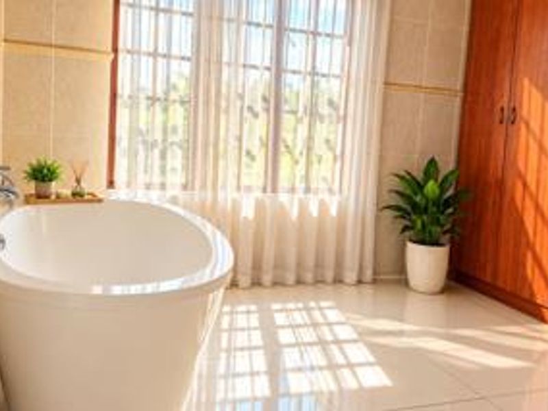 A bright and well-maintained bathroom featuring a modern freestanding bathtub, tiled finishes, and ample built-in wooden storage cabinetry.