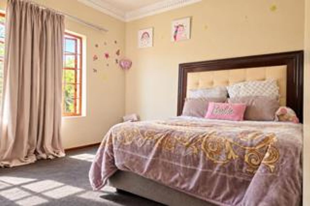 A well-lit bedroom featuring carpeted flooring, decorative cornice detailing, and a large window with timber frames.