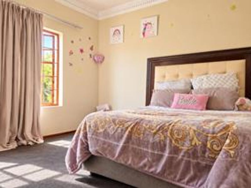 A well-lit bedroom featuring carpeted flooring, decorative cornice detailing, and a large window with timber frames.
