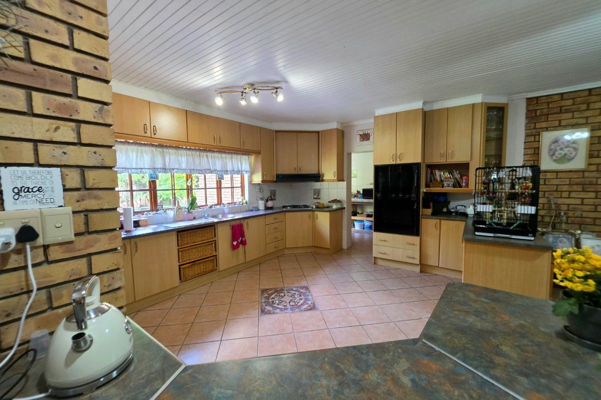 Spacious kitchen featuring light wood cabinetry, laminate countertops, built-in oven, and a distinctive exposed brick feature wall with tiled flooring.