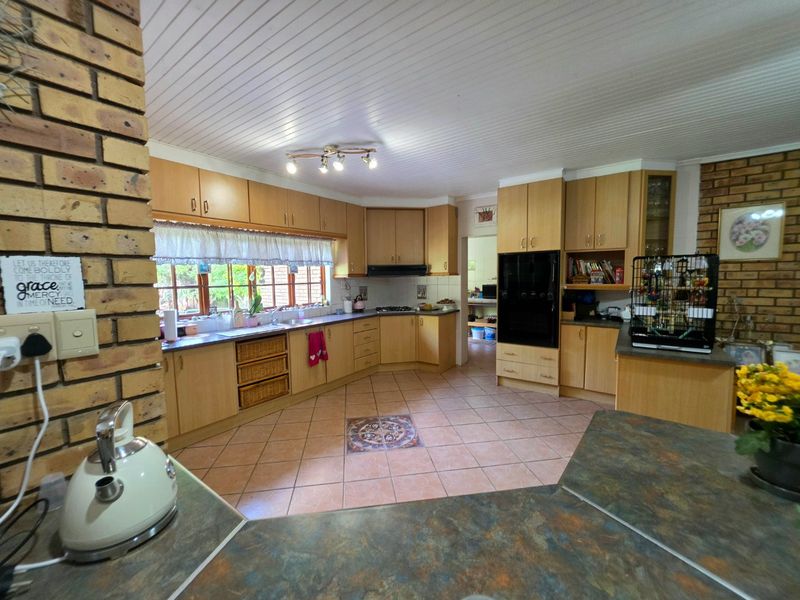 Spacious kitchen featuring light wood cabinetry, laminate countertops, built-in oven, and a distinctive exposed brick feature wall with tiled flooring.